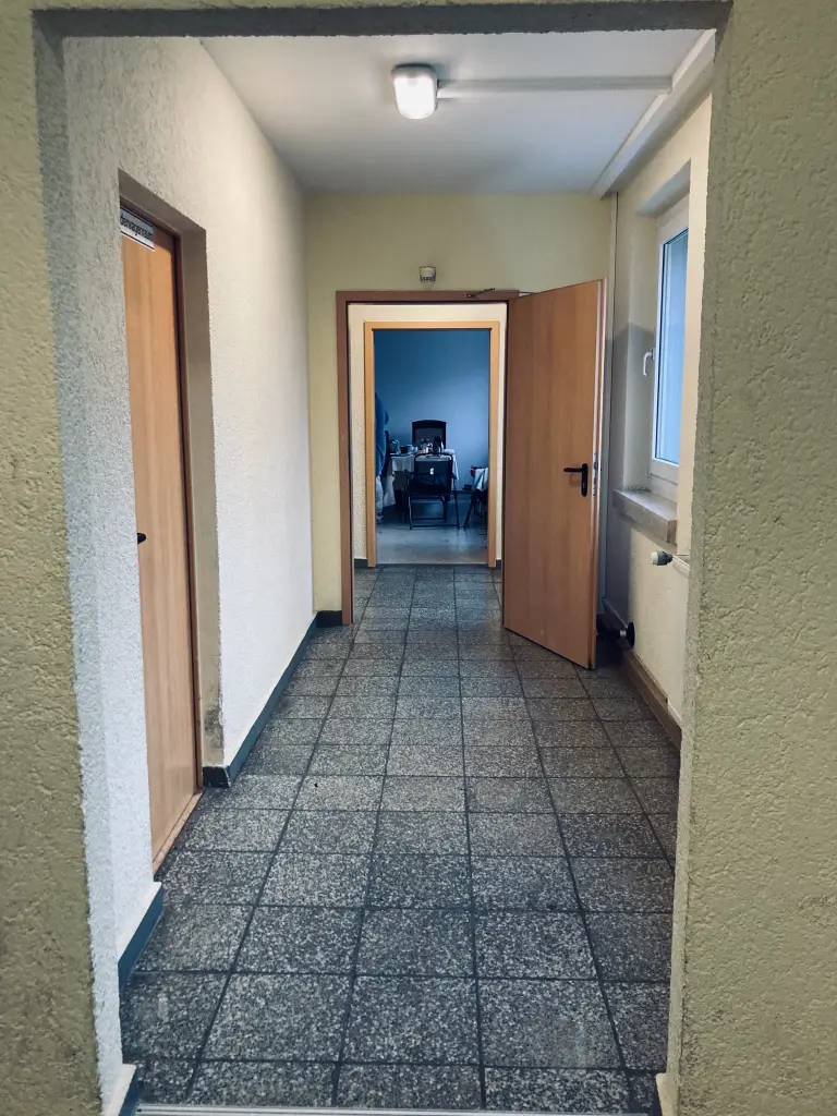 Ein schmaler Hausflur mit einer geöffneten Tür am Ende